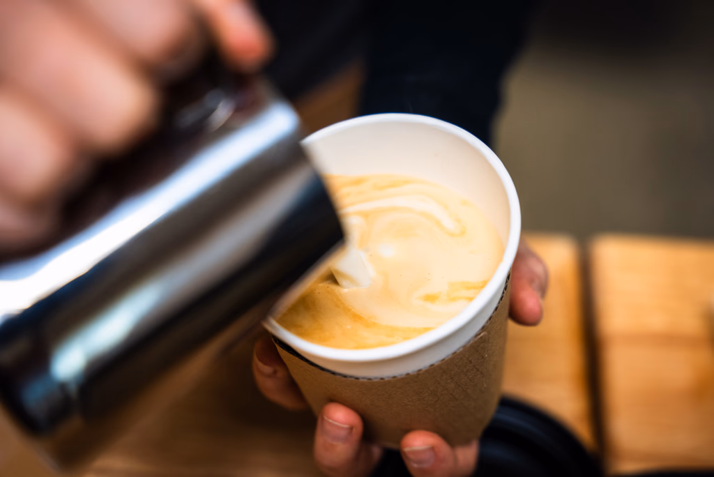 Barista pouring latte art into a cup at a Minneapolis coffee catering event